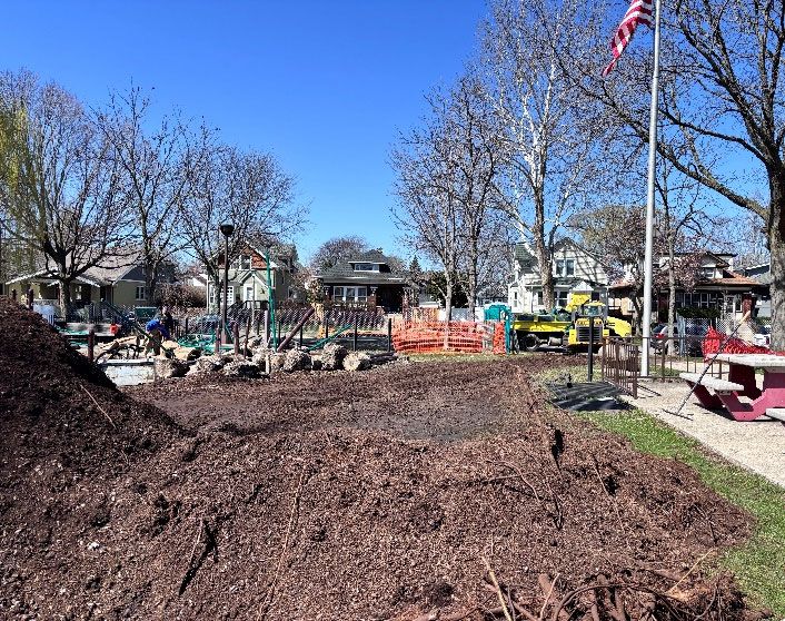 Andersen Park playground under construction with mulch piles, safety fencing, and heavy equipment.