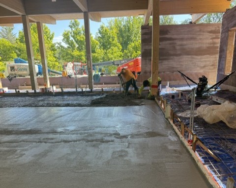 concrete workers spread wet concrete across the floor