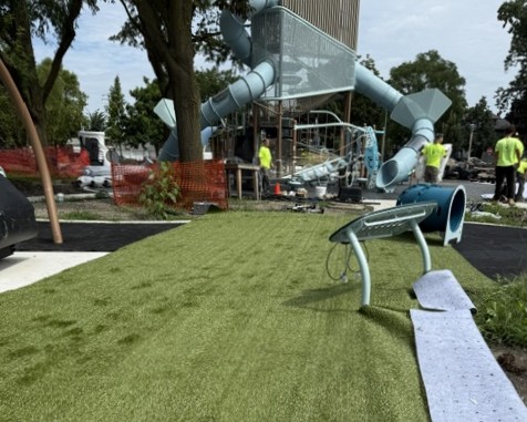 green turf coats the ground underneath the blue playground equipment