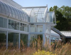 The Oak Park Conservatory features a white-trimmed glass structure with a curved roof and arched windows, surrounded by tall