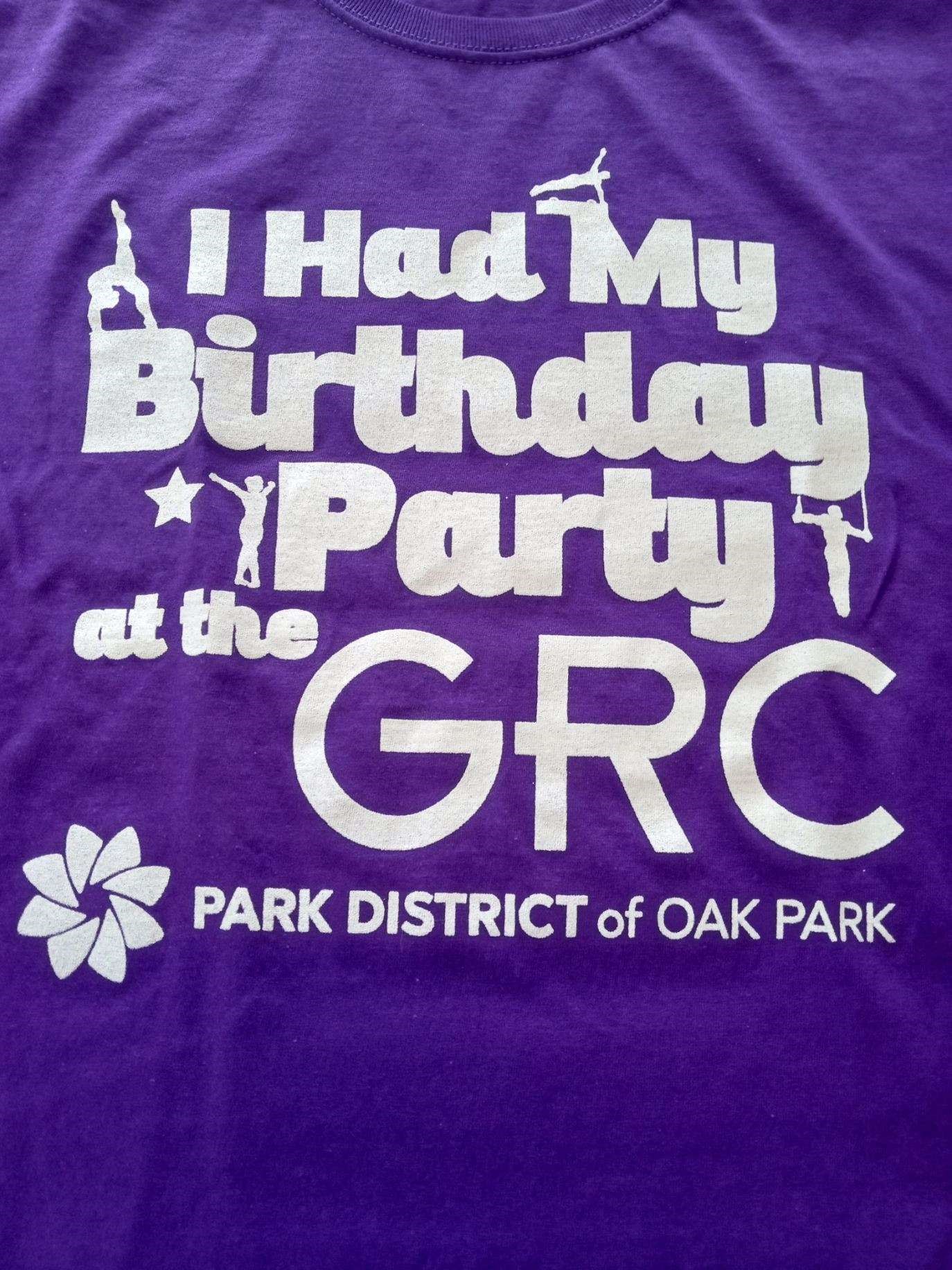 Purple t-shirt with white text: "I Had My Birthday Party at the GRC PARK DISTRICT of OAK PARK". Includes small gymnastics graphics.