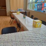 A long table is set for a Super Mario-themed birthday party with question block decorations and party favor bags.