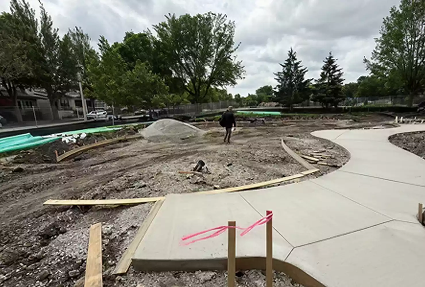 Longfellow Park construction site with new concrete pathways being laid and landscaping in progress.