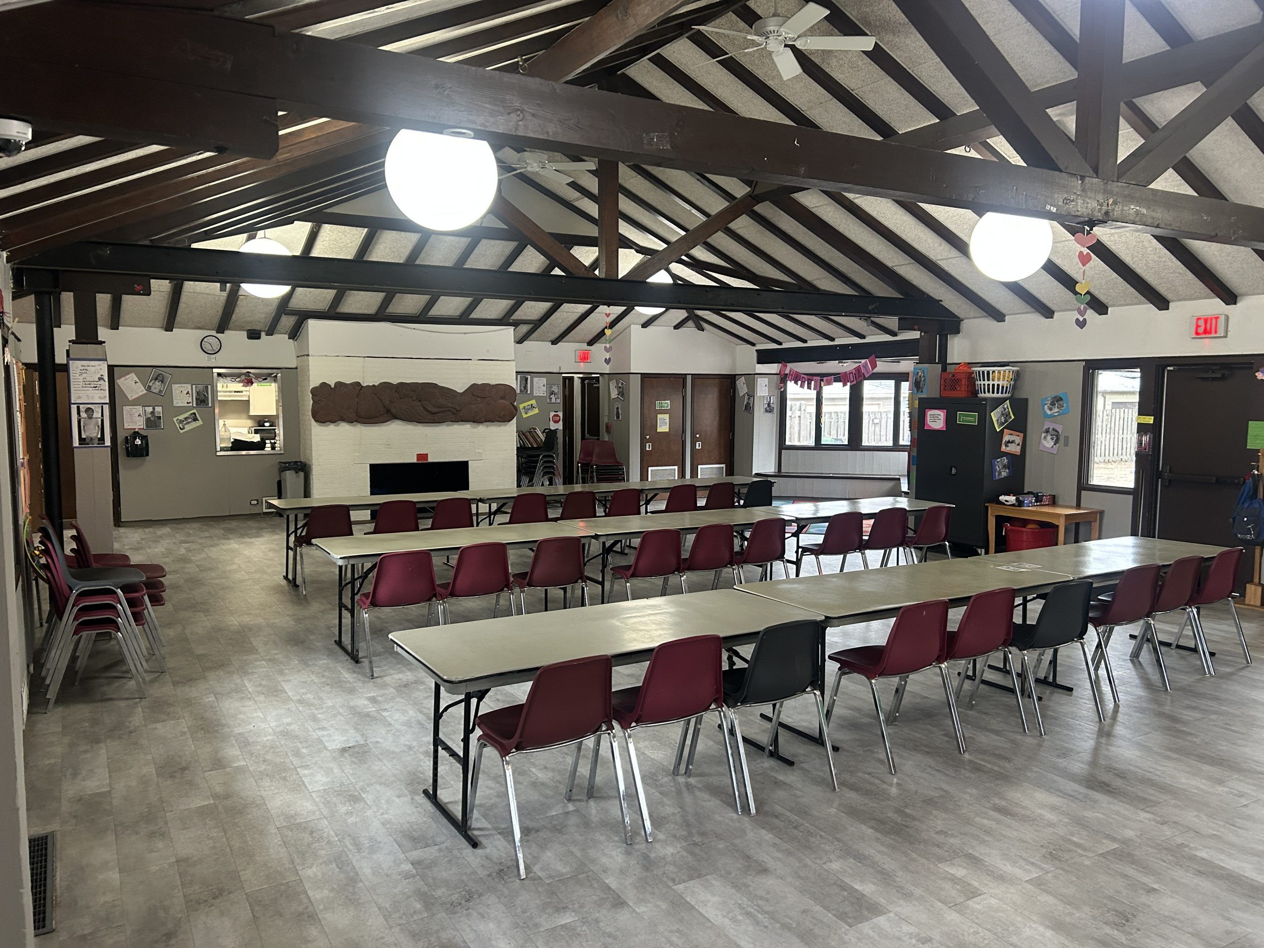 Andersen Room rental space set up with rows of tables and chairs, featuring a fireplace and a small kitchenette area.