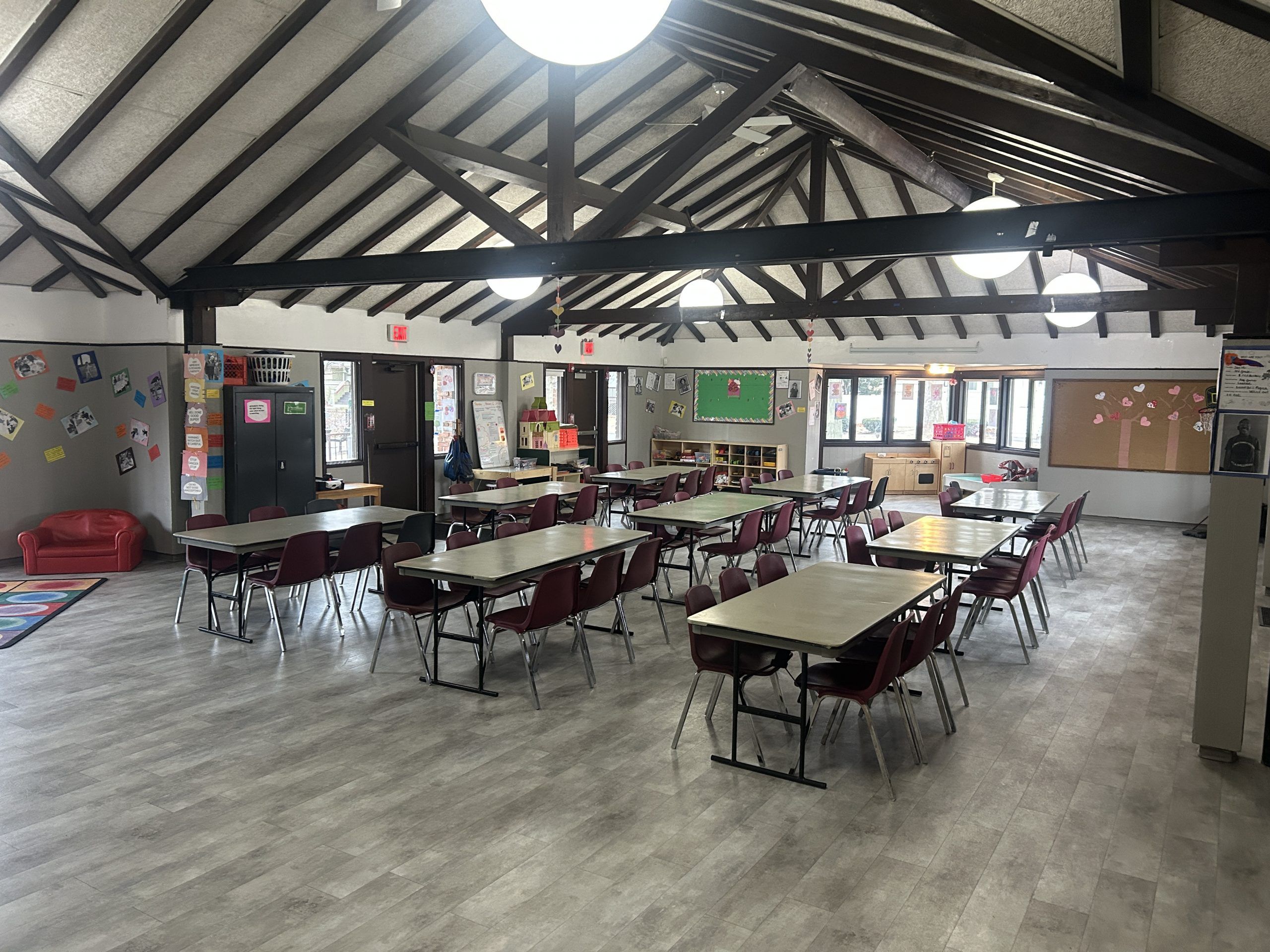 A spacious room with a high, beamed ceiling, set up with multiple tables and chairs, suitable for community events or rentals.