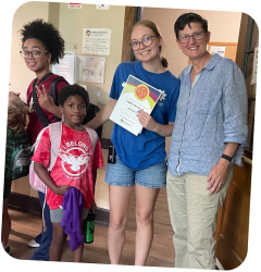 Three young people and an adult woman smile for a photo. One young person holds a certificate.