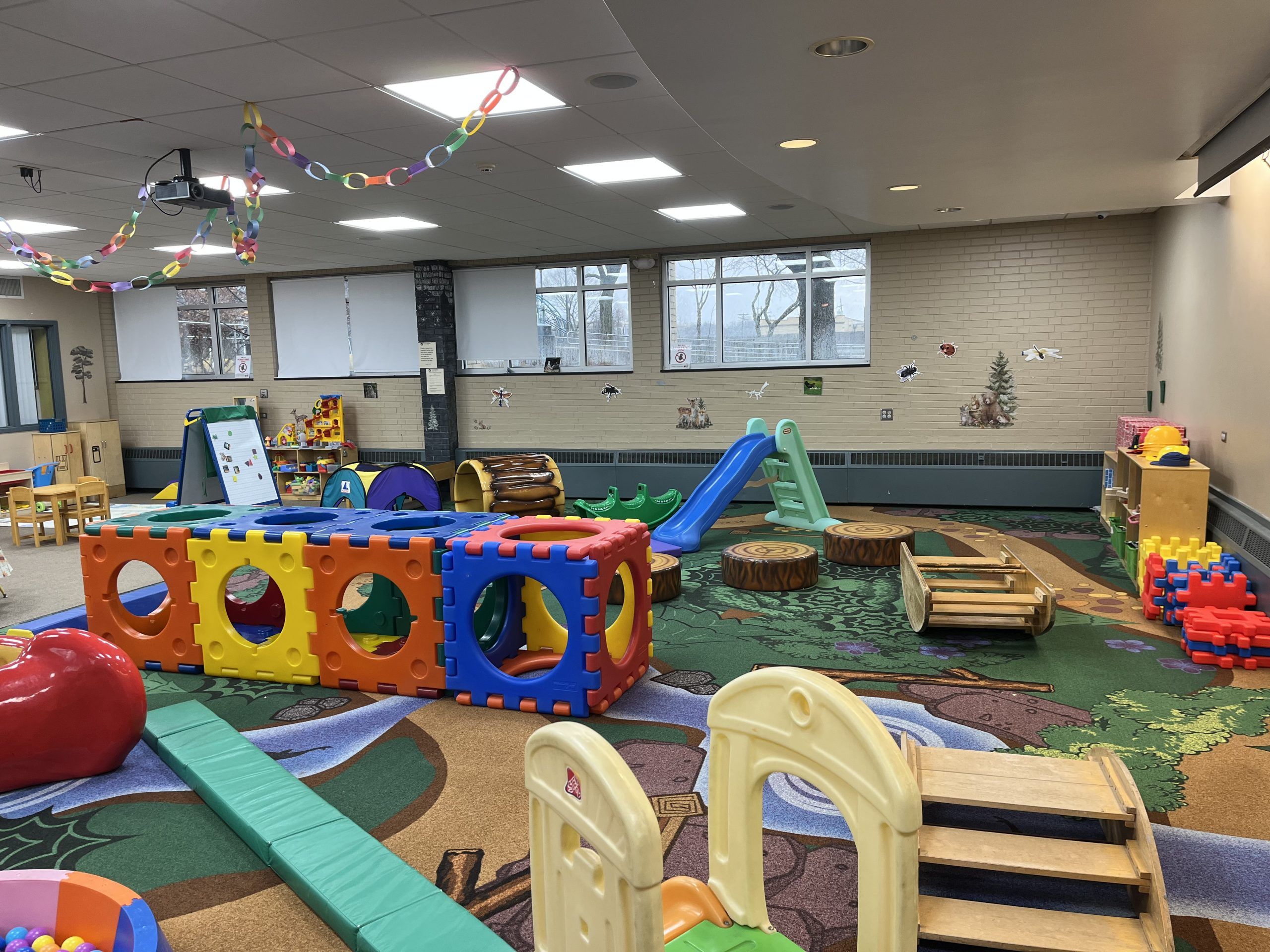 Colorful indoor playground with slides, tunnels, climbing blocks, and soft play structures for children.