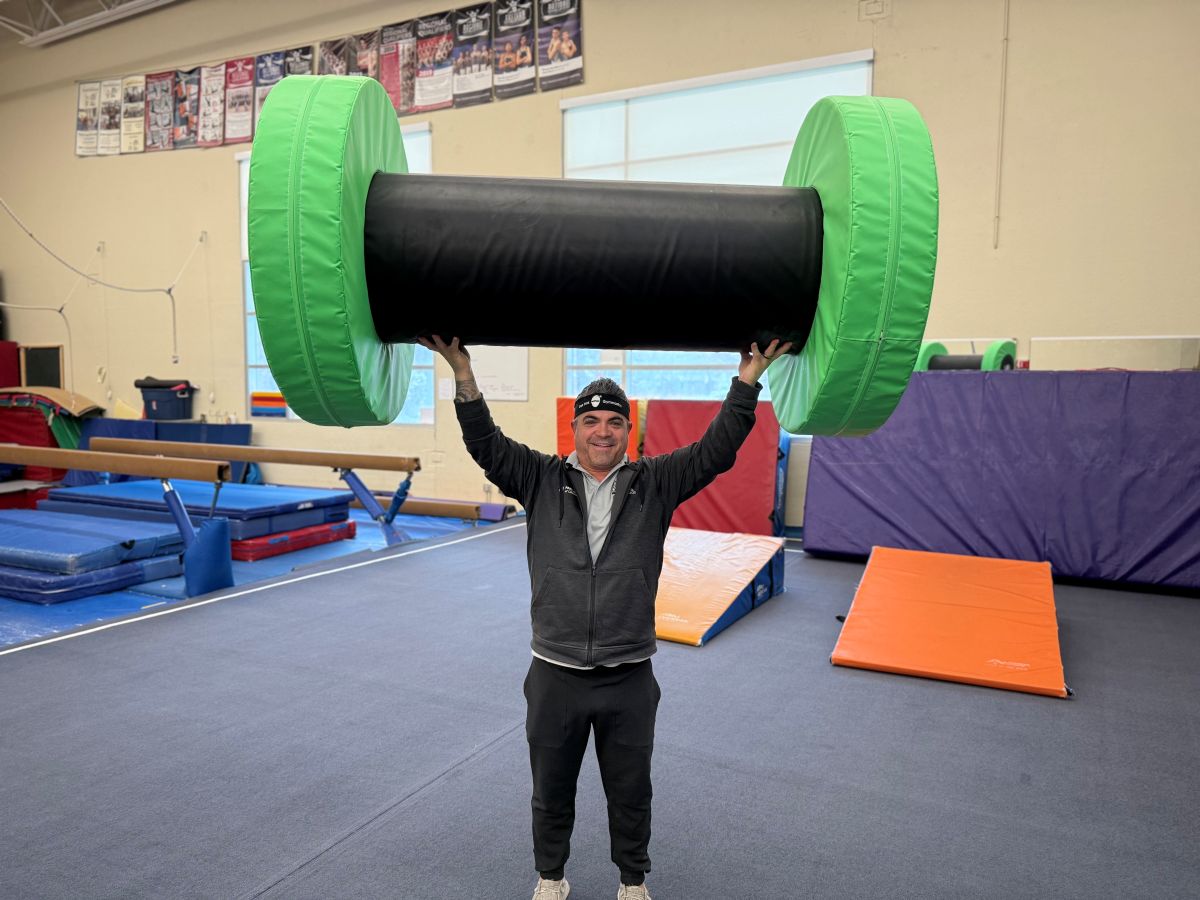 gymnastics supervisor holds his innovation award winner, the ninja axle wheel, above his head