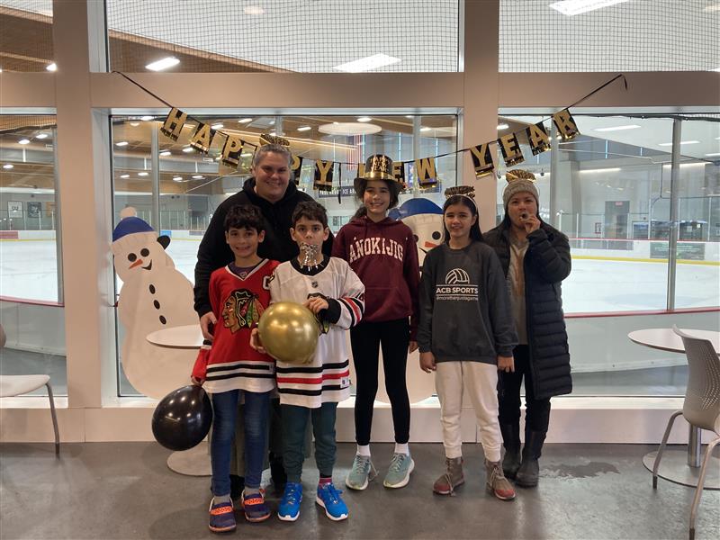 a family poses for a photo in front of a happy new year banner at the ice rink